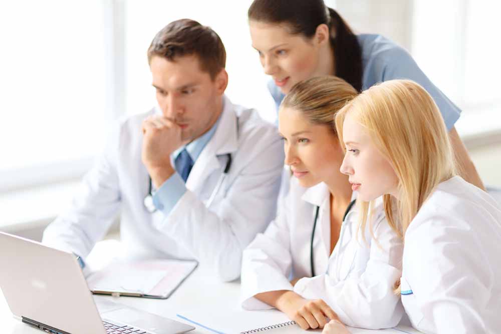 healthcare, medical and technology concept - busy group of doctors looking at laptop computer in hospital